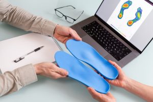 Custom Orthotics. Female Doctor Orthopedist Presents New Custom Made Insoles To A patient.
