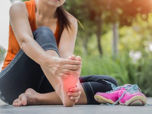 Pedorthist. Woman Massaging Her Painful Foot While Running