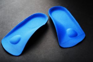 Pedorthic Clinic. Orthopedic insoles for correction of pronation of the foot on a dark background. 