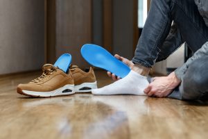 Custom Orthotics. Man putting new custom insole in a shoe. Feet recreation medicine concept.
