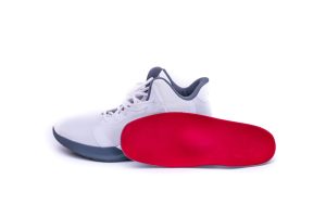 Custom Orthotics in Improving Athletic Performance. Modern mid-high white basketball shoes sneakers with custom-made orthotic inserts.