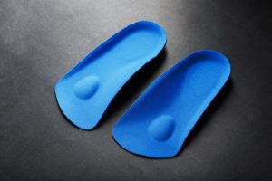 Custom Orthotics. Orthopedic insoles for correction of pronation of the foot on a dark background.