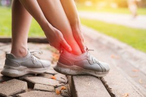 Custom Orthotics in Ottawa. foot discomfort. female joggers pain and discomfort after running in the public park. care and treatment for ankle injuries concept.