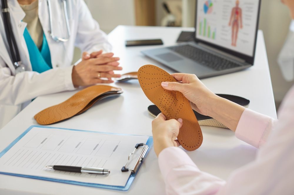 Can Orthotics Help Treat Plantar Fasciitis and Bunions? Custom orthotics. Patients hands holding leather orthopedic insole with pattern at orthopedists office for examination, custom insets for foot pain relief, comfortable walk. Shoe improvement, orthotic product concept.