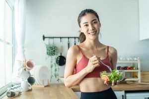 Why Choose Healthy Steps for Nutrition in Ottawa? Portrait of Asian attractive woman hold salad bowl and look at camera. Beautiful sport girl in sportswear enjoy eat clean vegetables after exercise for health in house. Diet and Healthy food concept.
