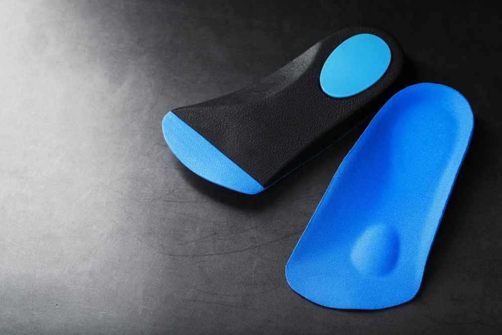Pedorthic Solutions: Improving Foot Comfort & Function? Orthopedic insoles for correction of the blue color of the foot on a black background. 