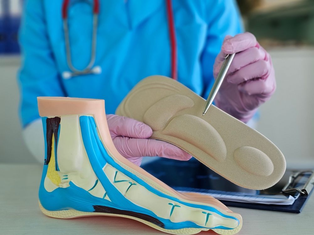 Pedorthic Solutions: Improving Foot Comfort & Function? Detailed examination of a foot model by a medical professional in a clinical setting.