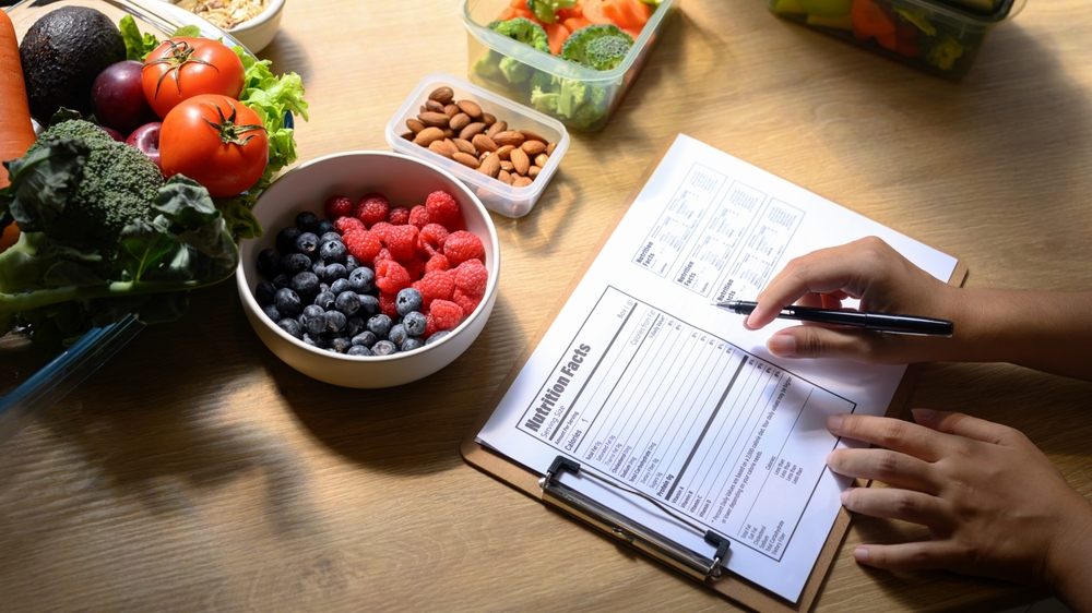 Fueling Your Ottawa Winter: Nutrition Tips for Staying Energized and Healthy? Nutritionist writing a healthy meal plan with fresh fruits, vegetables, and nuts on the table.