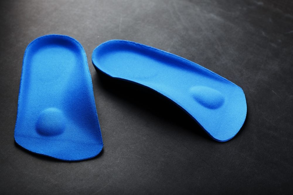 How Custom Orthotic Insoles Relieve Foot Pain & Improve Mobility in Ottawa? Orthopedic insoles for the correction of pronation of the foot on a dark background. Free space.