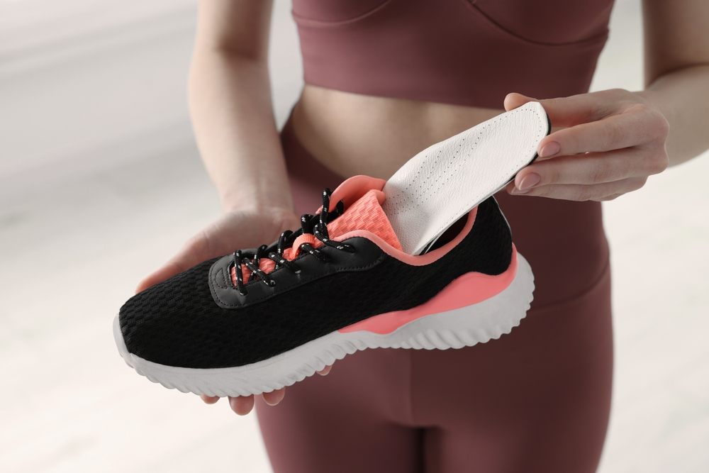 Step Into Comfort: Your Guide to Finding Orthopedic Shoes in Ottawa? Sporty woman putting an orthopedic insole into a shoe on a blurred background, close-up. Foot care.