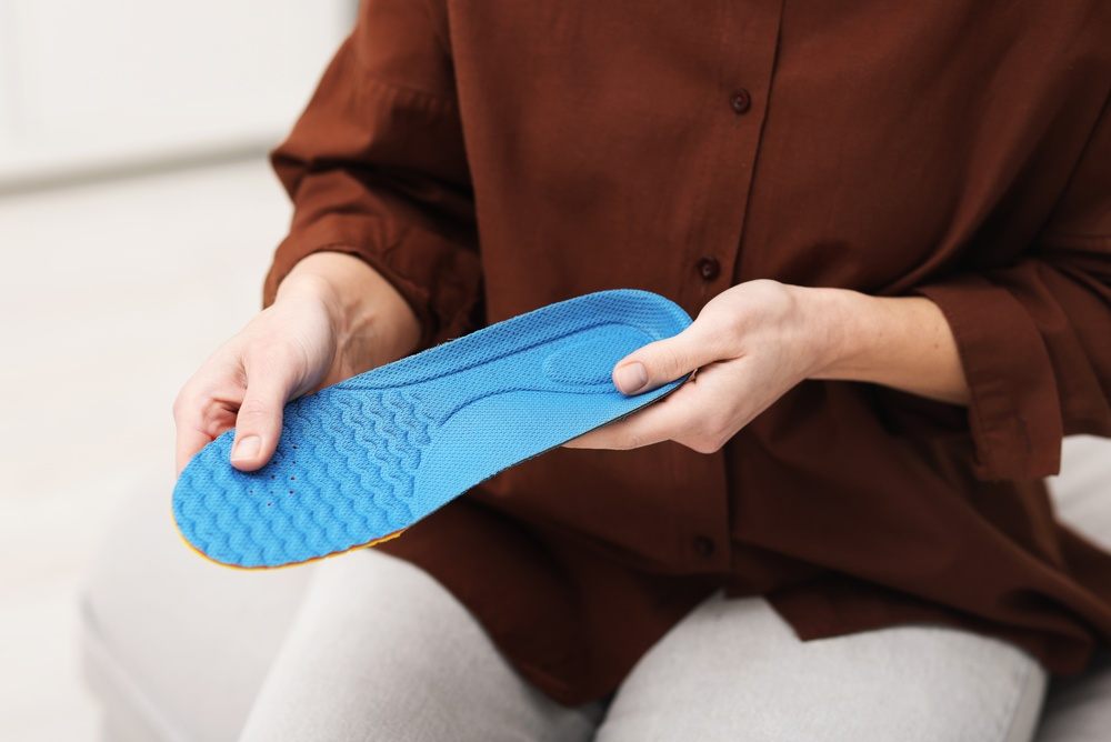 How Custom Orthotic Insoles Relieve Foot Pain & Improve Mobility in Ottawa? Woman with orthopedic insole at home, close-up.