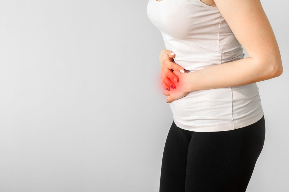Why Am I Always Bloating? And What Can I Do About It? A woman with her hands holding her stomach. Medical or gynecological problems, healthcare concept.