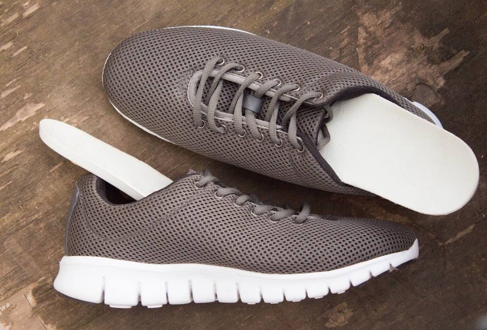 How to Choose the Best Orthopedic Shoes for Specific Foot Conditions. Insoles and sports shoes on old wooden board. Prevention of orthopedic foot diseases, foot care. Rustic background. Top view.