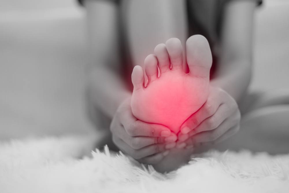 How Orthopedic Shoes Support Foot Health Beyond Just Comfort. woman having barefoot pain while sitting on the couch at home. Foot ache due to Plantar fasciitis and waking long. Health and medical concept